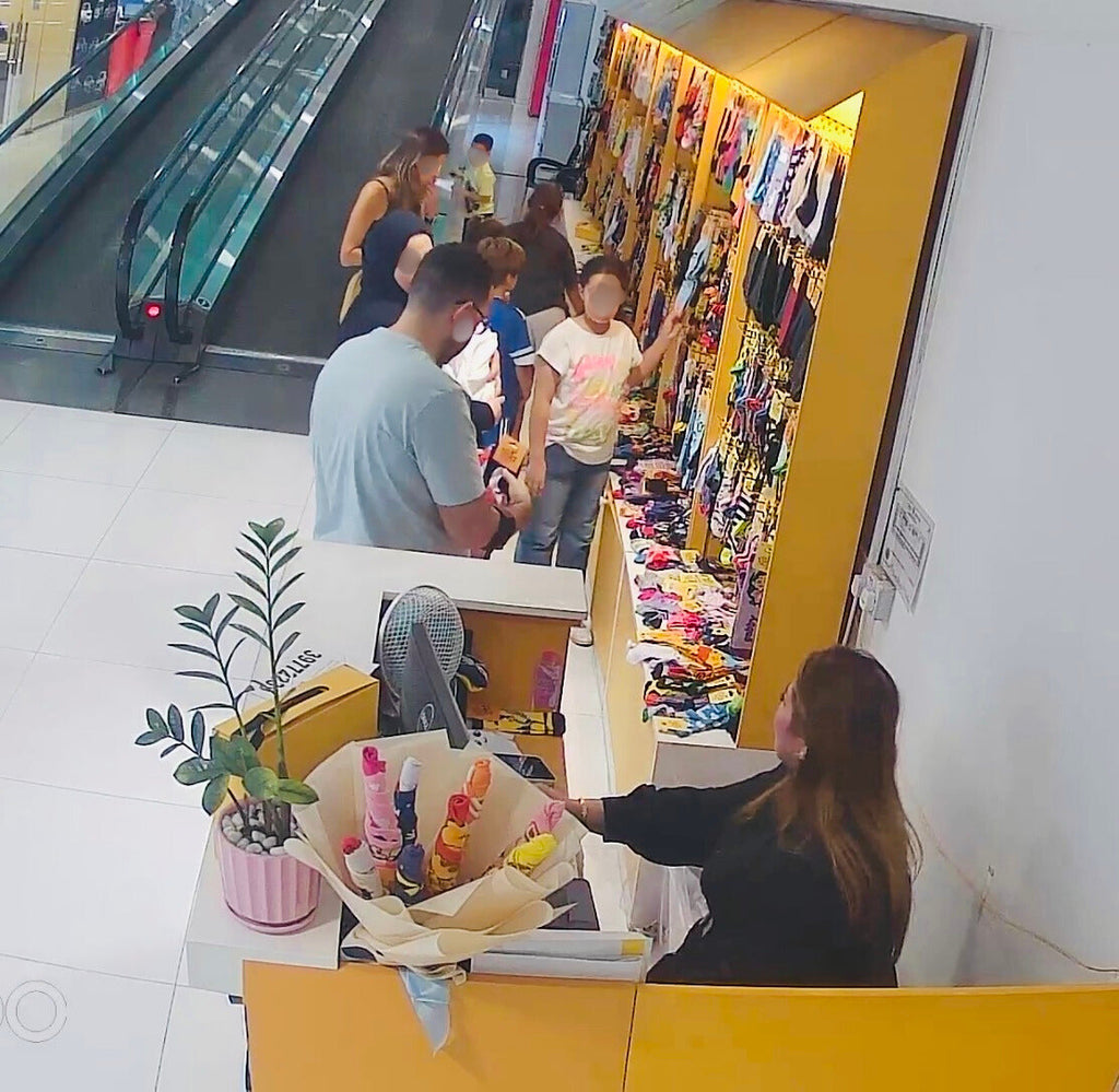Customers shopping at Socks Store in Bahrain, surrounded by colorful mismatched socks promoting Odd Socks Day and anti-bullying awareness.