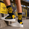 Black and yellow crew socks inspired by Al Ittihad Club colors, featuring striped football-style graphics, Arabic text, and socksstore.net branding near the foot area.