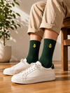 Dark green crew socks featuring a small embroidered avocado design near the cuff.