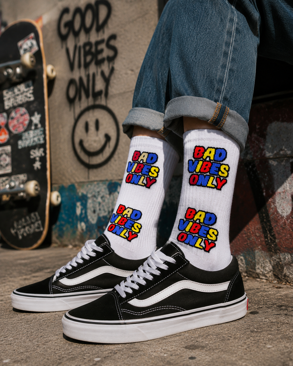 White crew socks featuring colorful “BAD VIBES ONLY” text graphics in a bold comic-inspired streetwear design.