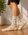 Beige crew socks featuring an all-over pattern of cute puppy faces.