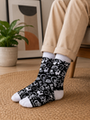 Black and white crew socks featuring hand-drawn doodles, light bulbs, arrows, stars and abstract symbols