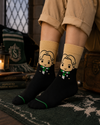 Black and beige crew socks featuring a cute wizard-inspired character with blonde hair and a green striped scarf in a minimalist cartoon style.