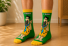 Green Fred Flintstone cartoon crew socks with colorful prehistoric character design