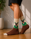 Crew socks featuring a stylish deer character wearing a green suit on a beige and brown background.