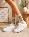 Beige crew socks featuring funny sloth character wearing traditional Arab Gulf outfit design.