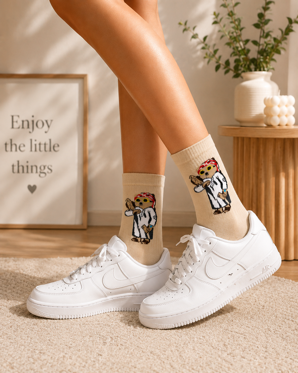 Beige crew socks featuring funny sloth character wearing traditional Arab Gulf outfit design.