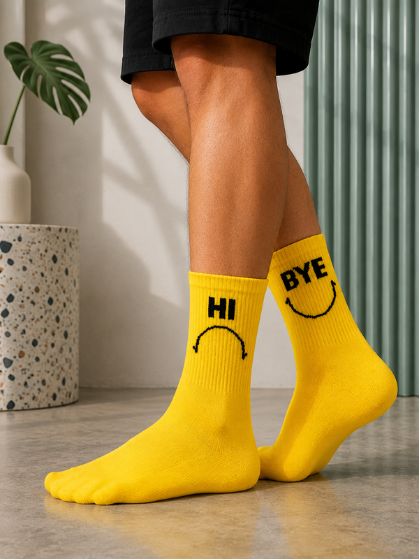 Yellow mismatched crew socks featuring a sad HI face on one sock and a smiling BYE face on the other.