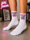 White crew socks featuring the phrase "It's Not Easy To Be A Bitch" in black and pink lettering.