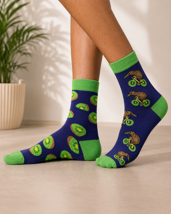 Mismatched crew socks featuring kiwi fruit slices on one sock and kiwi birds riding bicycles on the other.