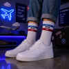 White ribbed crew socks with blue and red stripe details featuring the text “LET’S FLY UP” in a clean sporty retro style.