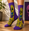 Purple crew socks featuring a neon yellow skeleton graphic design with edgy streetwear style