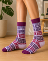 White crew socks with repeated OK Boomer text in purple, burgundy and red with dark purple cuffs and toes