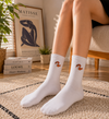 White crew socks with orange snake embroidery design on the upper side.