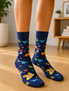 Navy blue crew socks featuring a cute giraffe wearing party glasses with colorful confetti, streamers, and hearts on a soft cotton fabric.