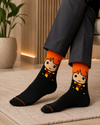 Black and orange crew socks featuring a cute wizard character with orange hair and a striped scarf.