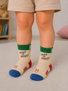 Toddler wearing colorful Take It Easy crew socks for kids aged 2–3 years.