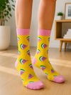 Pair of yellow crew socks featuring an all-over pattern of pink watermelon slices with green rinds and pink cuffs, heels, and toes on a white background.