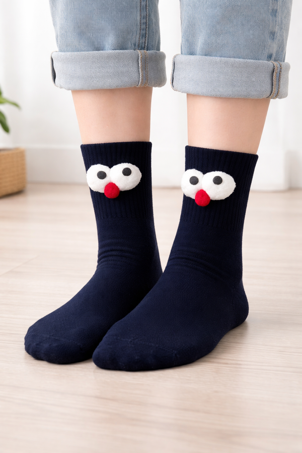 Front view of black googly eyes crew socks with fluffy white eyes and pink nose cartoon design on a clean background.