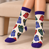 Bahraini Na'al Socks featuring colorful traditional Bahraini slipper patterns in red, blue, green and black on a cream background with purple cuffs and toes.