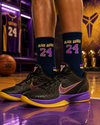 Dark navy crew socks with Black Mamba 24 text and purple yellow striped sports design.