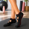 Black Pilates grip socks with crossover straps and non-slip grip dots on the sole