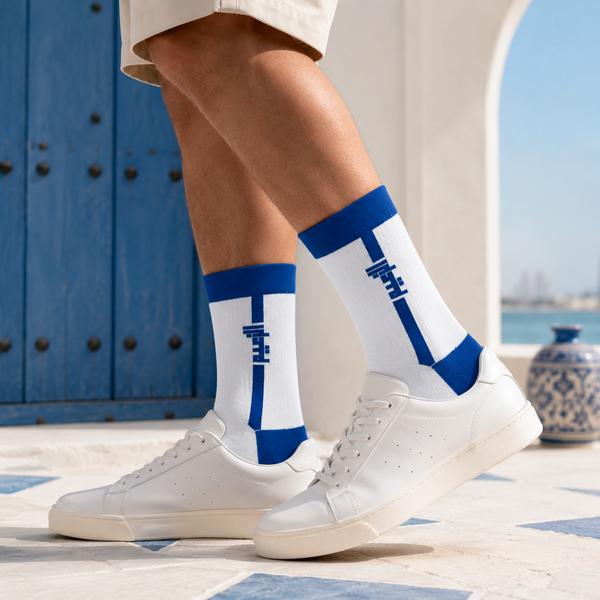 White and royal blue crew socks featuring a vertical Arabic calligraphy-inspired design with socksstore.net branding near the foot area.
