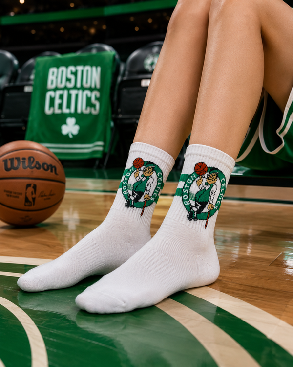 White crew socks featuring a vintage Boston Celtics basketball logo with green stripes and retro sports styling.