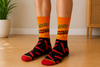 Orange and black Cheetos Flamin’ Hot crew socks with spicy snack pattern design