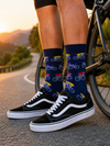 Model wearing colorful bicycle pattern crew socks with navy background and multicolor bicycle illustrations.