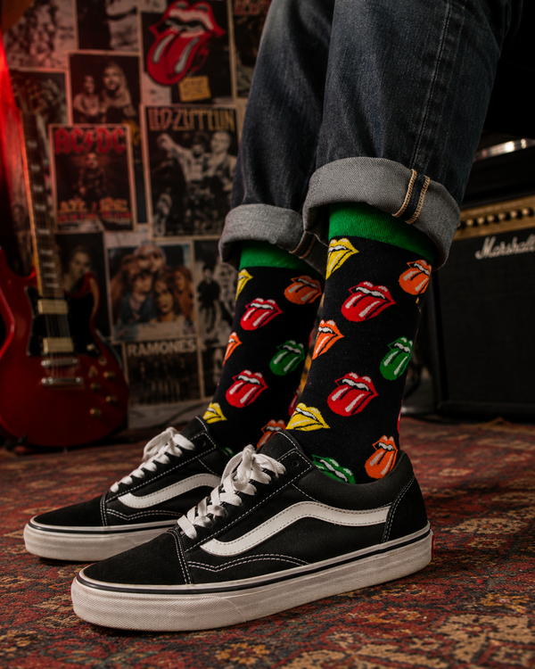 Black crew socks featuring colorful tongue and lips graphics in a bold retro rock-inspired pop art design with green and blue accents.