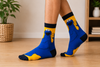Yellow Cookie Monster cartoon socks holding a cookie with blue character design