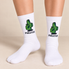 Model wearing white crew socks featuring a green pixel-style cactus graphic with Fucktus text, legs only with shoes off.