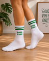 White crew socks with green stripes and the phrase "Good Vibes" embroidered in green lettering.