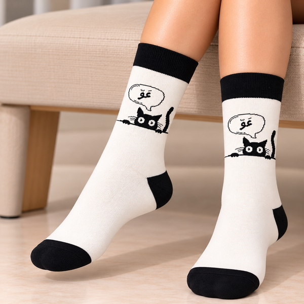Meow Cat Socks featuring a playful black cat peeking over a line with an Arabic meow speech bubble, white fabric, black cuffs, heels and