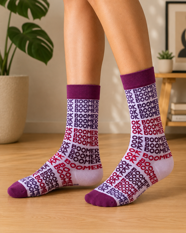 White crew socks with repeated OK Boomer text in purple, burgundy and red with dark purple cuffs and toes
