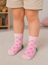 Light pink kids crew socks with bright pink polka dots and green heel accents for toddlers aged 2–3 years.