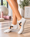 White crossover Pilates grip socks with black crisscross straps and non-slip sole