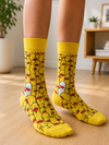 Pair of bright yellow crew socks featuring a crowd of cartoon yellow ducks with one white duck on a white background.