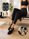 Black Pilates grip socks with cross straps and non-slip sole designed for yoga, barre, and fitness training.