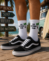 White crew socks with Do Nothing Club text and small green palm tree design.