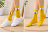 Front view of yellow cartoon face socks with fluffy white eyes and red nose design on a clean background.
