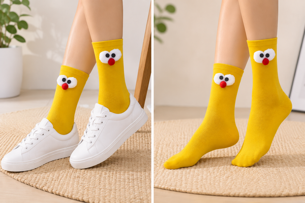 Front view of yellow cartoon face socks with fluffy white eyes and red nose design on a clean background.